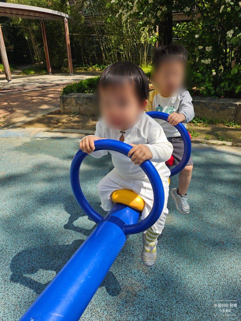 A toddler riding a seesaw at a Korean daycare center